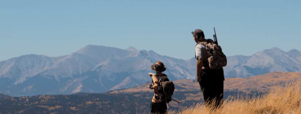 An image of an adult hunter and youth hunter in the middle of grass field while hunting in Nevada