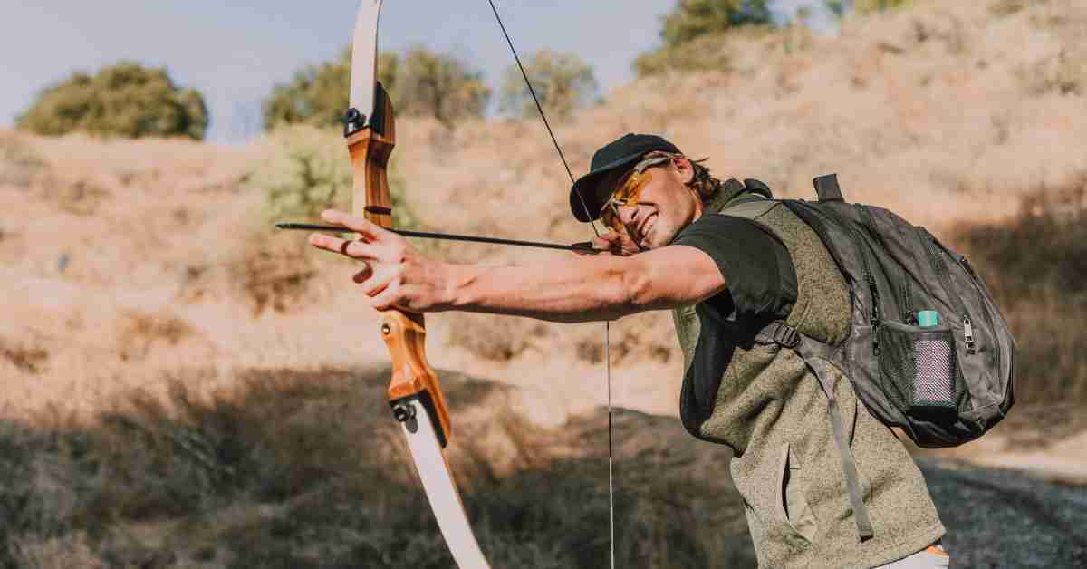 A hunter in a middle of open field, ready to take a shot with his hunting recurve bow