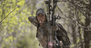 A woman hunter aiming her bow towards a game species, ready to draw using the best hunting thumb release
