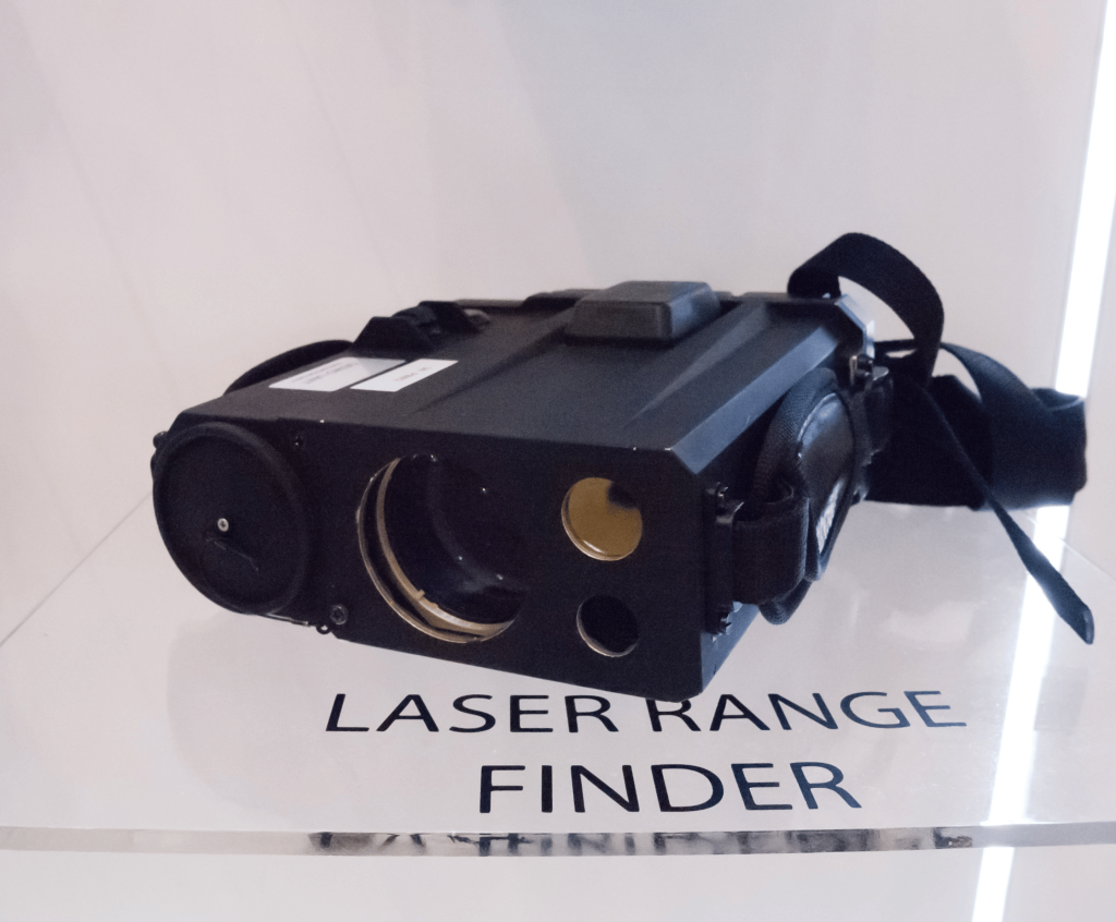 A black laser rangefinder on a white, clean surface