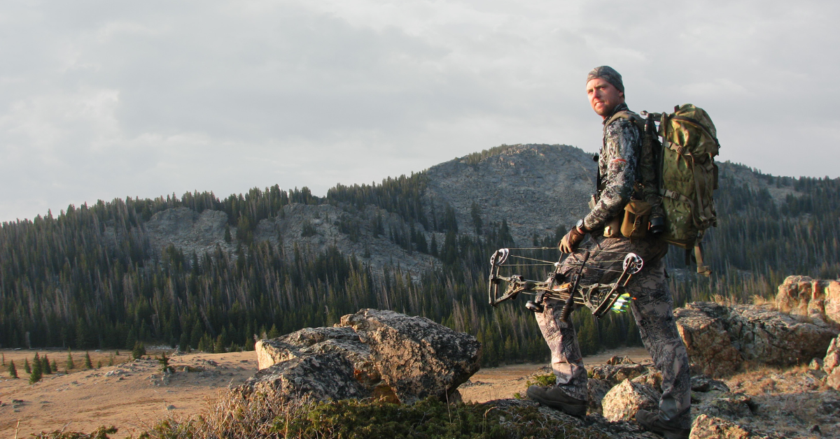 An image of a bow hunter carrying a nicely organized saddle hunting pack setup on his back